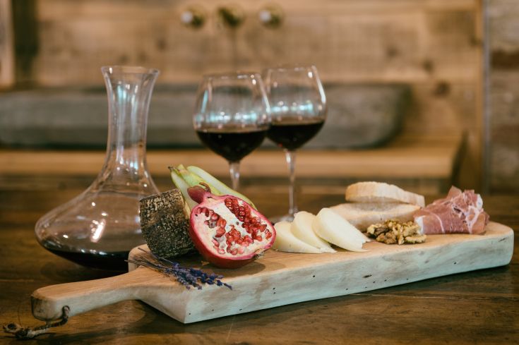 A platter with cold cuts, cheese, fruit, and red wine, perfect for a simple aperitif.
