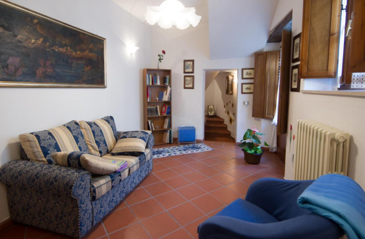 Soggiorno semplice con un divano e una libreria, in uno spazio curato.
