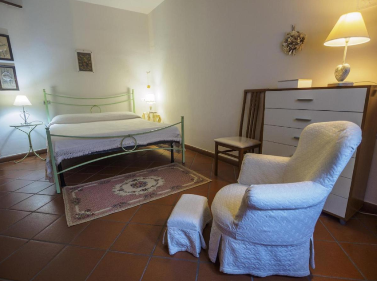 Ampia camera con letto matrimoniale e area relax all'interno di un palazzo a Spello.