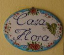 Una targa con il nome 'Casa Flora', utilizzata come identificazione per l'abitazione.