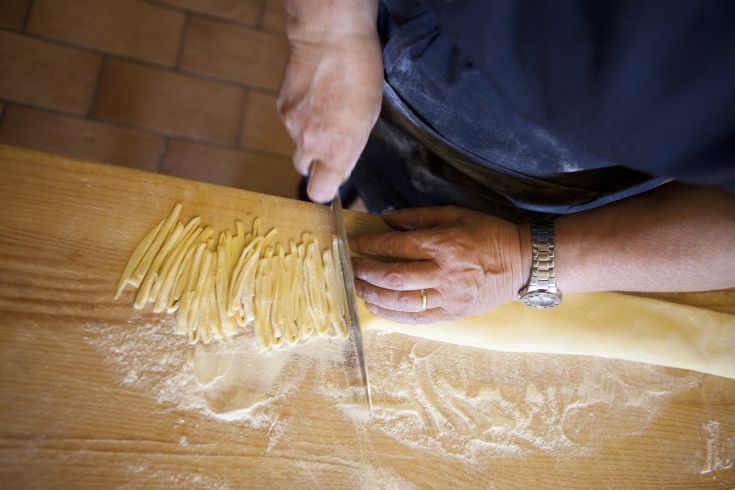 Preparazione artigianale della pasta in un ambiente rustico.