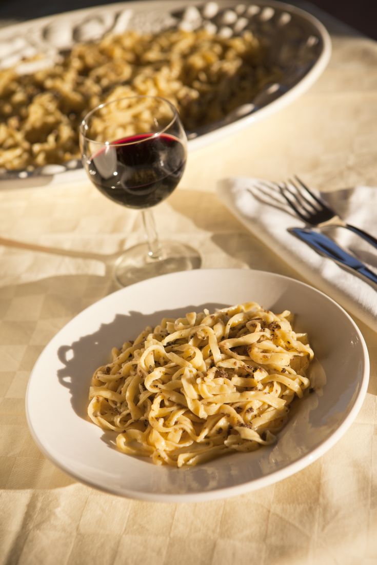 Un piatto di pasta caldo con vino rosso, presentato su una tavola curata.