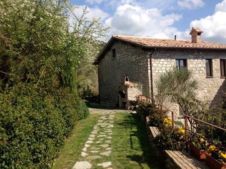 A simple path leading to an ancient stone cottage surrounded by lush vegetation.