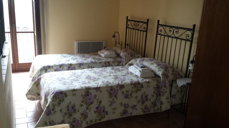 Simple room with twin beds, featuring floral decorations and a calm atmosphere.