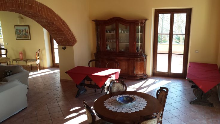 Spacious room with traditional decor, featuring red wooden tables and natural lighting. Perfect for relaxation.