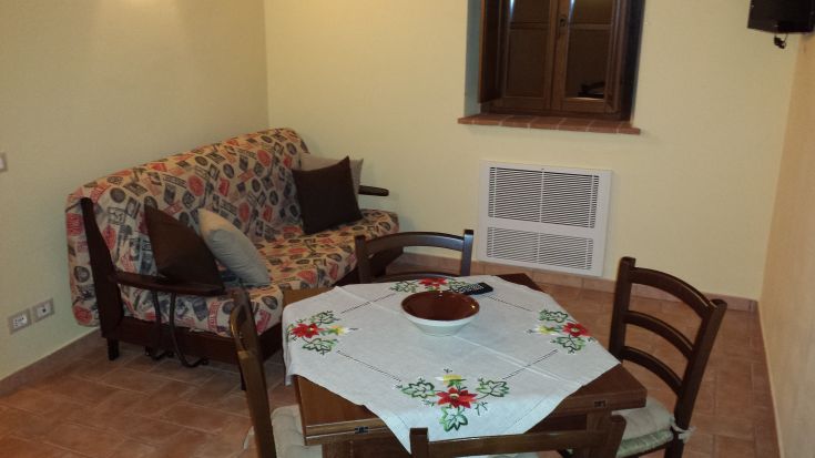 A simple living room with a sofa, table, and a window that provides natural light, perfect for relaxing moments.