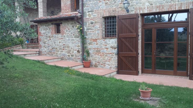 A stone farmhouse scene with a garden and stairs, surrounded by nature.