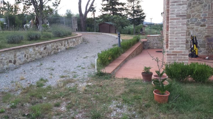 A path leads to a cottage surrounded by lush greenery, trees, and a tranquil atmosphere.