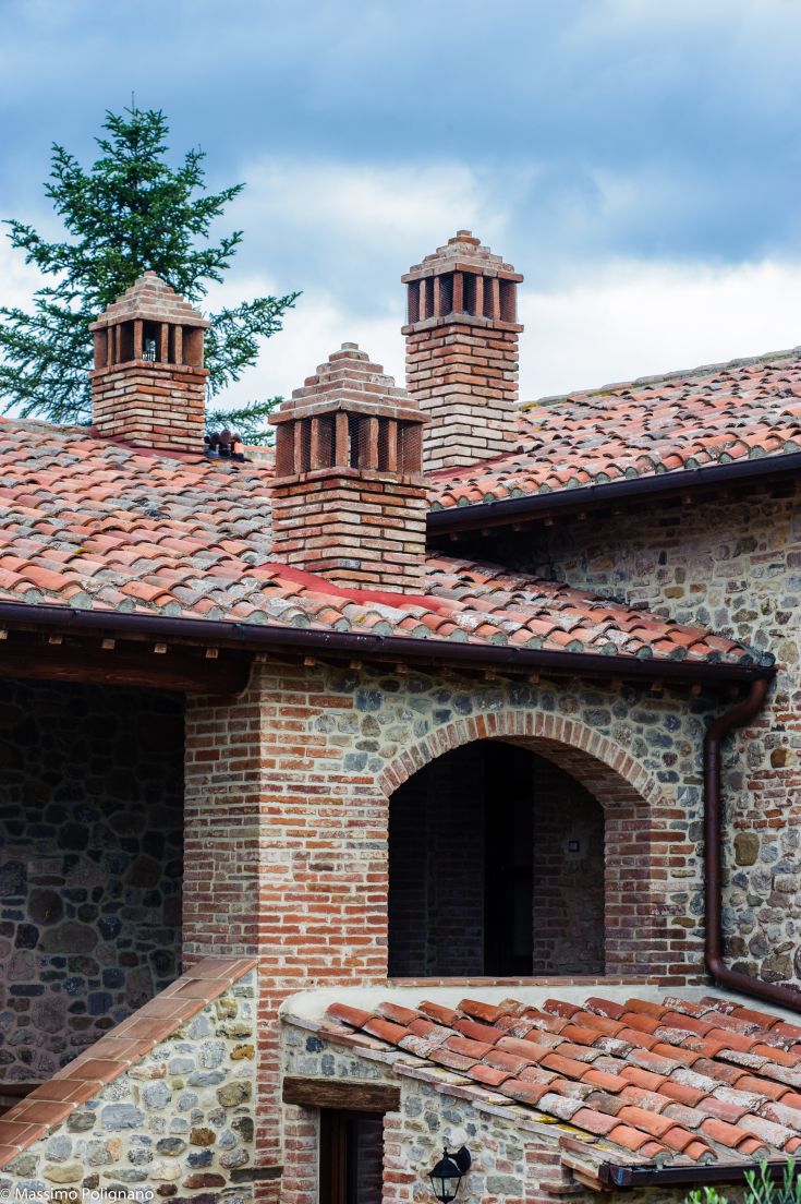 A close-up of simple chimneys on a building with a tiled roof and stone details.