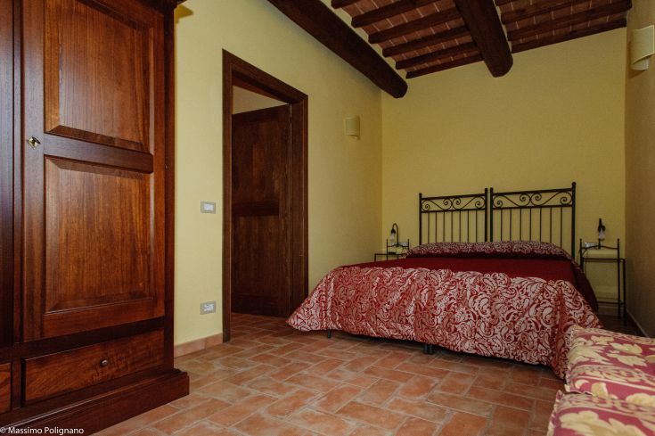 Simple room with a double bed and wardrobe, featuring warm tones and a calm atmosphere.