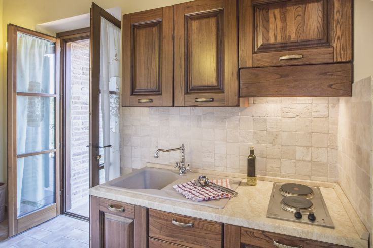 Spacious kitchen with wooden furniture, featuring a sink and a stove, perfect for family gatherings.