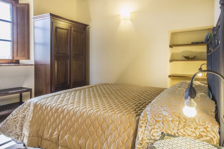 Cozy space featuring a double bed, wooden wardrobe, and soft lighting.