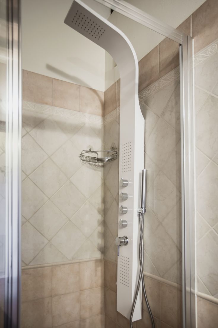 Simple shower in a bright tiled space with practical accessories.