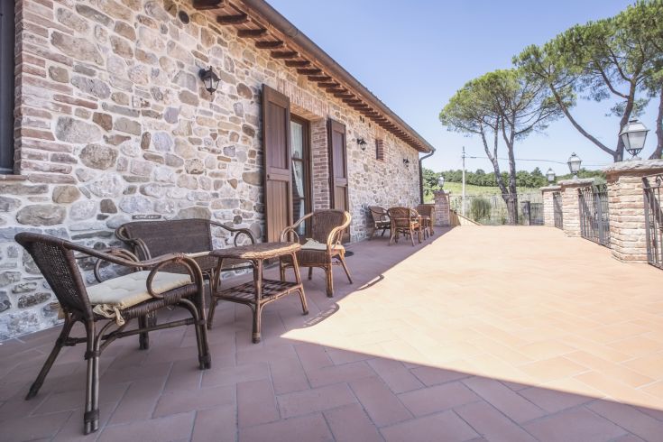 Bright terrace of a renovated building, surrounded by natural agricultural landscape.
