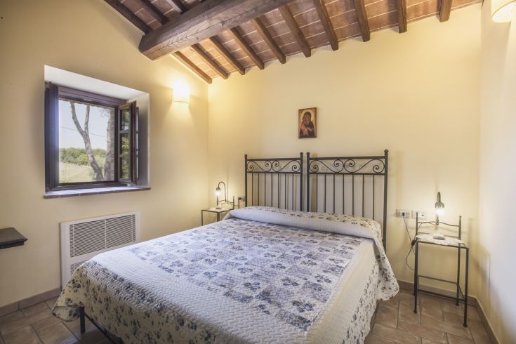 Cozy bedroom with a double bed and a view of gentle hills.