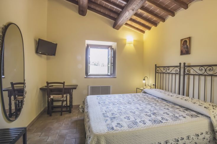 A cozy room with a double bed, minimalist decor, natural light, overlooking a green lawn.