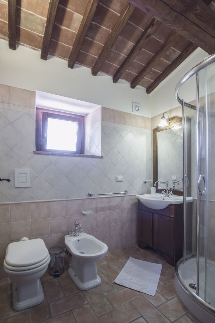 Modern bathroom interior featuring light tiles, wooden ceiling, and a well-finished shower.