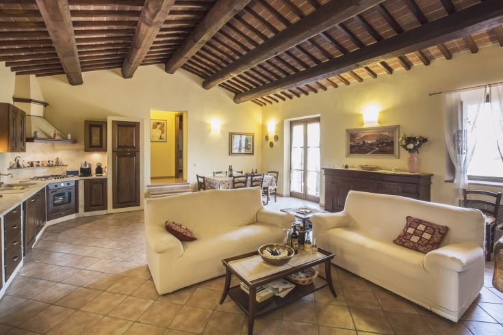 A bright open space room with wooden beam ceiling and integrated kitchen.