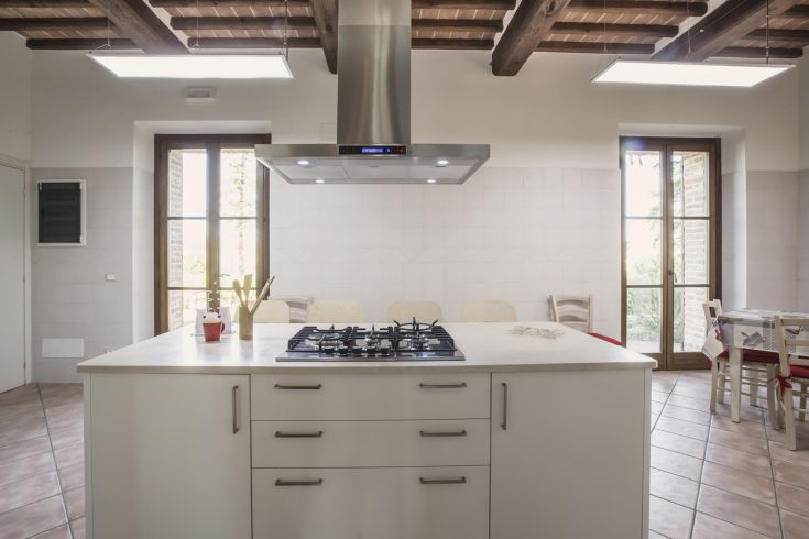 A well-lit kitchen featuring a large central island and simple decorative elements.