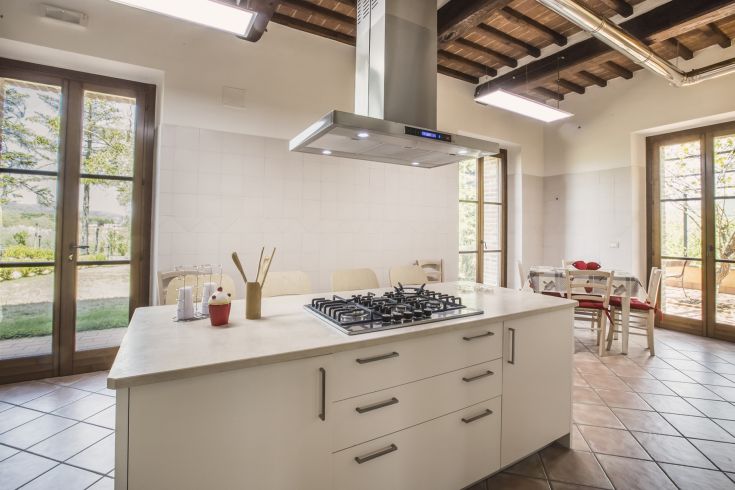 Contemporary kitchen with a central island and large windows allowing natural light to enter.