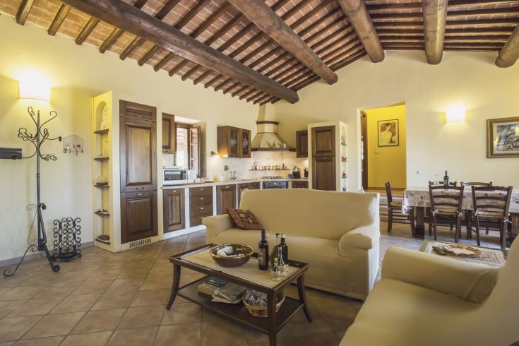 Simple interior of a palace featuring a bright kitchen and living room with wooden furniture and exposed beams.