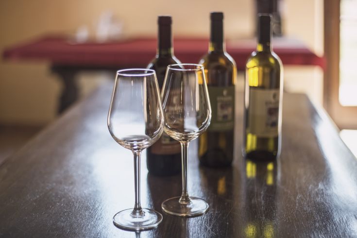 Two wine glasses in focus, surrounded by bottles in a casual and welcoming venue.