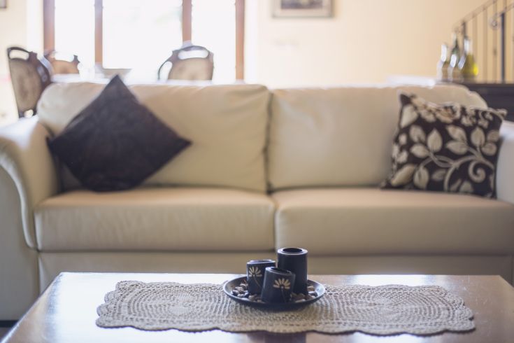 A simple living room with a white sofa, decorative cushions, and a modest centerpiece.