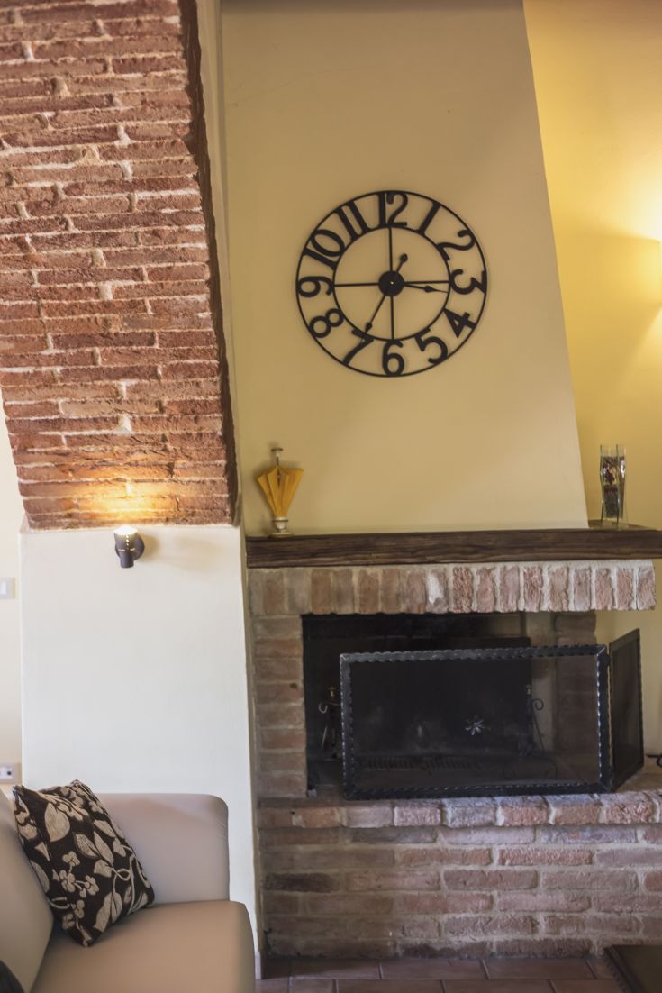 A cozy corner featuring a fireplace, vintage clock, and a brick wall.