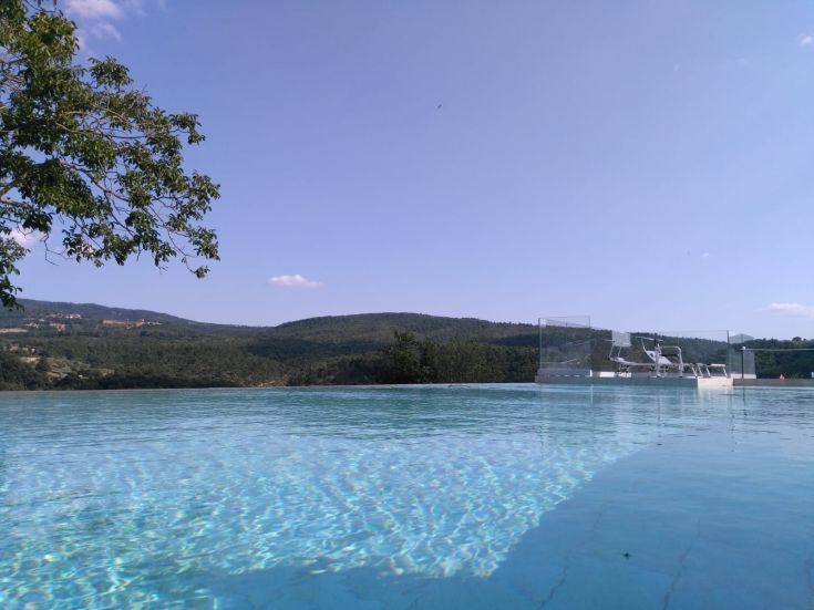 A poolside view showcasing lush green hills and a clear sky.