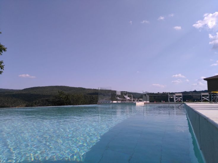 A pool nestled in greenery with a view of gentle surrounding hills, perfect for outdoor relaxation.