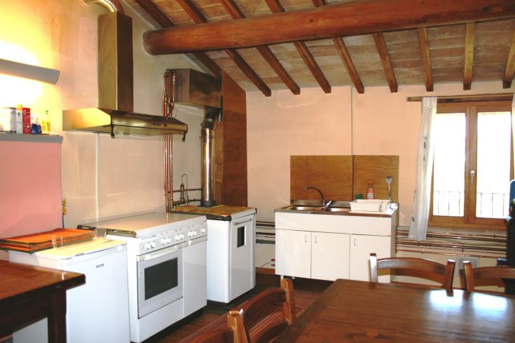 Spacious, bright kitchen featuring exposed beam ceiling and well-equipped cooking area.