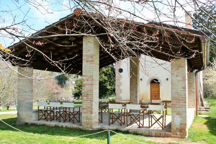 A building immersed in greenery, featuring outdoor tables and chairs to enjoy the fresh air.