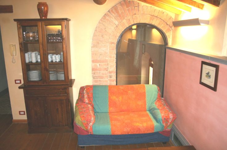 A simple living room with a vibrant-colored sofa and wooden furniture, surrounded by a natural setting.