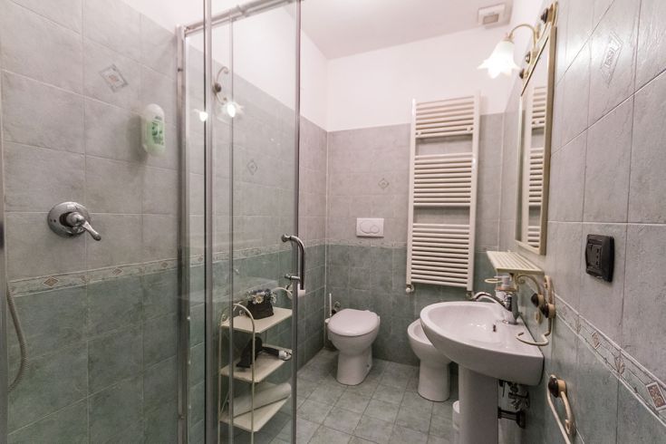 Bagno semplice e confortevole con piastrelle verdi e doccia. Spazio ideale per gli ospiti.