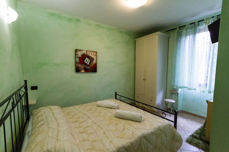 Camera semplice con pareti verdi e televisione, adatta per momenti di riposo.