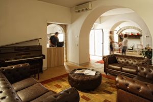 Spazio lounge tranquillo con divani in pelle e un pianoforte in un ambiente sobrio.