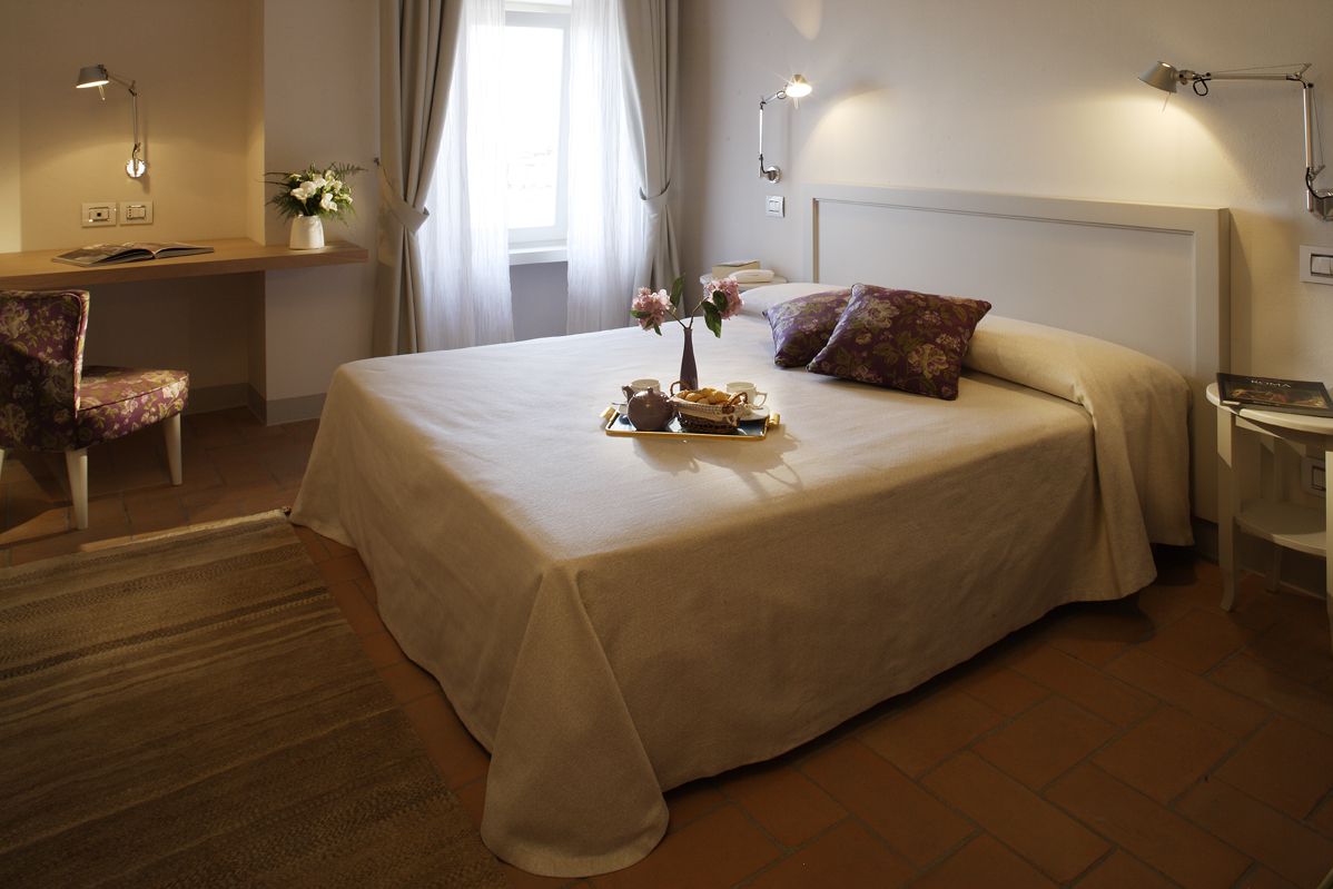 Una camera semplice con letto matrimoniale, scrivania e alcune piante decorative.