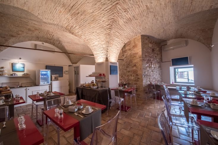 Interno di un ristorante con archi in mattoni e tavoli in stile contemporaneo.