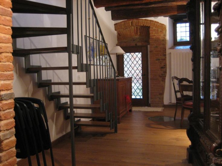 Interior of a palace featuring a wooden and metal staircase, spacious areas, and simple details creating a welcoming atmosphere.