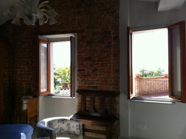 Interior of a house with stone walls and windows overlooking a tranquil landscape.
