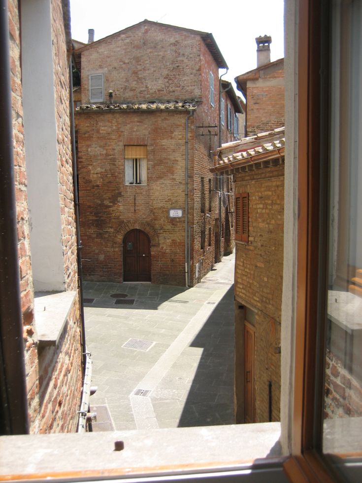 Narrow alley in a historic center, featuring ancient buildings and brick walls.