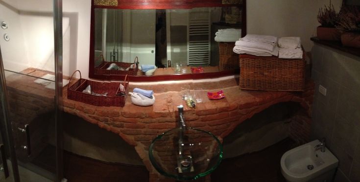 Bathroom with brick finishes, a mirror, and neatly arranged towels.