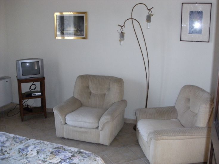 A cozy and inviting corner with armchairs, a television, and a lamp in a minimalist setting.