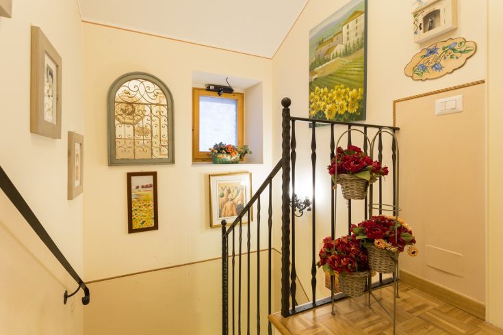 Scala con decorazioni semplici e fiori appesi. Ambiente luminoso e accogliente.