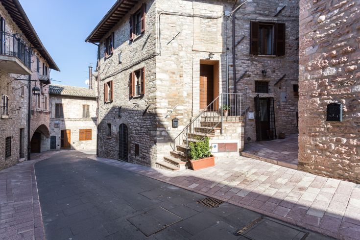 Una strada tranquilla di un borgo con edifici in pietra, finestre e semplici tratti architettonici.