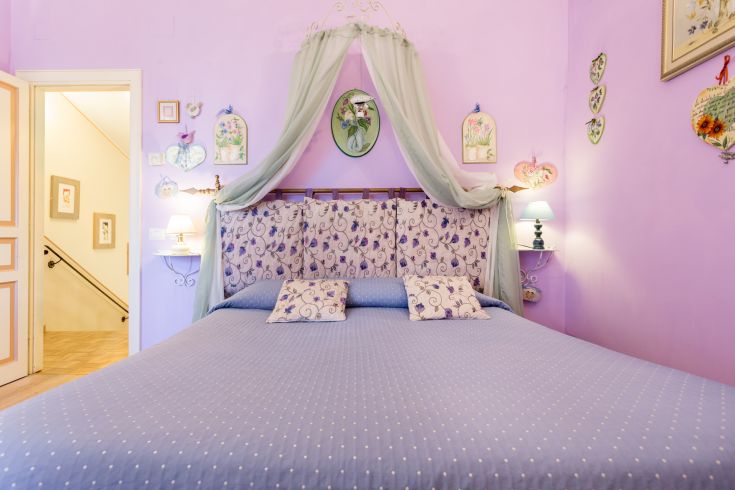 Camera con tonalità lilla e decorazioni semplici, adatta per un soggiorno tranquillo.