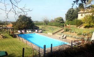 Piscina all'interno di un giardino ordinato, accanto a un palazzo storico caratteristico dell'Umbria.