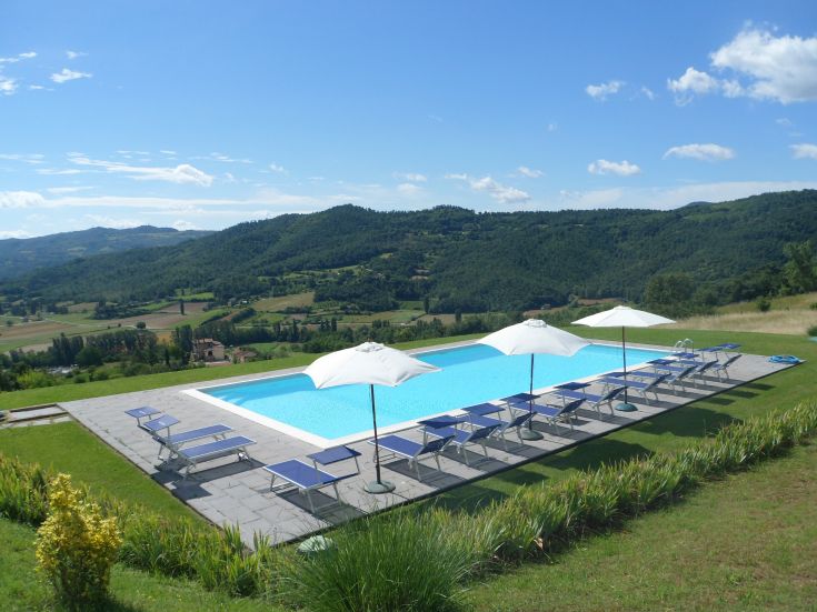 Une piscine située dans la campagne ombrienne, entourée de collines verdoyantes.