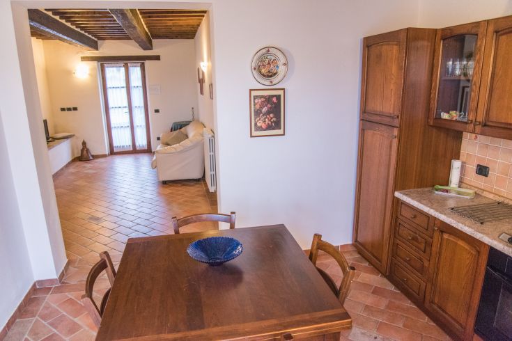Cuisine ouverte spacieuse avec une table en bois, reliée à un salon lumineux.