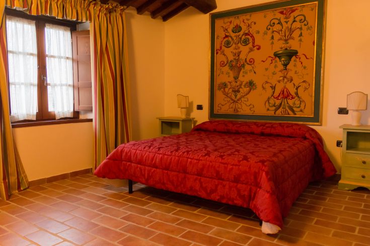 Chambre fonctionnelle dans un agriturisme en Ombrie, avec un lit rouge et une décoration simple.